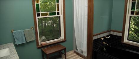 Une salle de bain avec une fenêtre, une baignoire et un petit banc en bois.