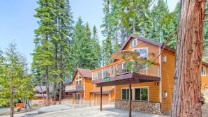 A two-story wooden cabin with a balcony, surrounded by tall pine trees. - Explorers Retreat (Yosemite National Park)