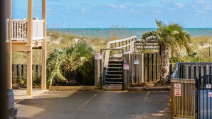 Une porte en bois qui mène à une zone de plage offrant une vue sur l’océan.
