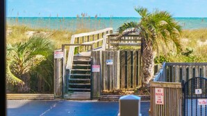 Une porte en bois qui mène à une plage d’où l’on a une vue dégagée sur l’océan.