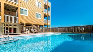 Une piscine avec des chaises longues et une clôture en bois.