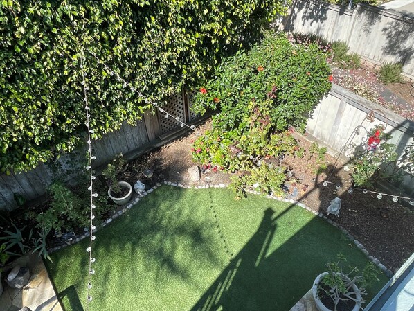 Enjoy a serene outdoor space surrounded by lush plants and a small tree with vibrant flowers.