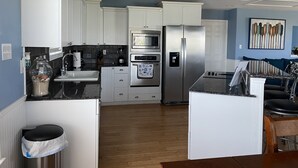 A modern kitchen with white cabinets, stainless steel appliances, and a wooden floor.
