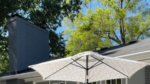 Una terrazza esterna con tavolo e sedie, un ombrellone e un barbecue.