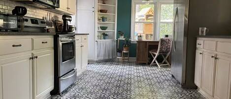 A kitchen with white cabinets, a microwave, a stove, and a patterned floor.
