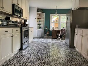 A kitchen with white cabinets, a microwave, a stove, and a patterned floor.