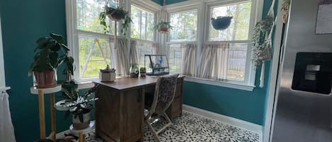 Een keuken met blauwgroene muren, een vloer met patroon, een houten tafel en hangende planten.