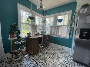 A kitchen with teal walls, a patterned floor, a wooden table, and hanging plants.