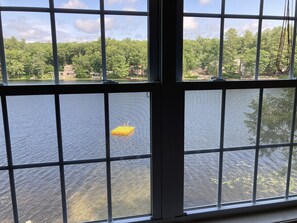 Overlooking a serene body of water, this room offers a glimpse of a buoy and a natural landscape with trees and buildings.