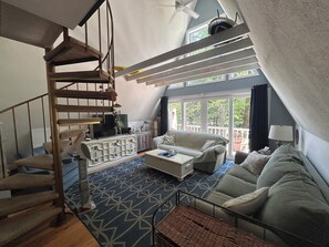A spacious living area with a staircase, a sofa, a coffee table, and a television.