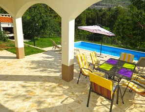 Un patio couvert avec une piscine, des chaises et une table.