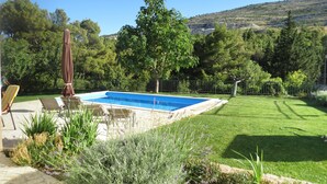 A rectangular swimming pool with a stone border, surrounded by a well-maintained lawn and various plants. - A Mountain Escape From Everyday Life At Apartment Vilar right next to Split! (Srinjine, Split)
