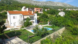 A residential area with houses, a swimming pool, and a mountainous backdrop. - A Mountain Escape From Everyday Life At Apartment Vilar right next to Split! (Srinjine, Split)