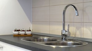 A modern kitchen with a stainless steel sink, a wooden tray with cherries, and a white cabinet. - A Mountain Escape From Everyday Life At Apartment Vilar right next to Split! (Srinjine, Split)