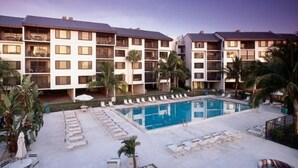 Ein Hotel mit Poolbereich, mehreren Balkonen und Palmen.