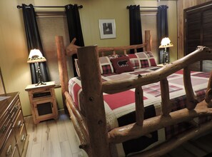 Una cama de madera con cabecera, una mesita de noche con lámpara y una colcha acolchada.