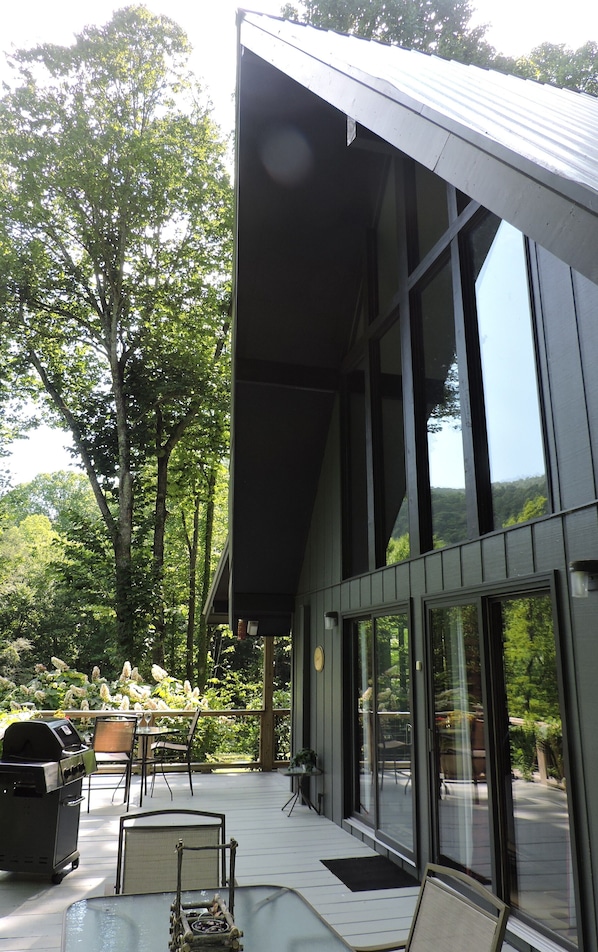 Un edificio moderno con amplios ventanales, un porche cubierto y mesas al aire libre.