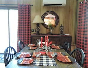 Una mesa de comedor dispuesta con platos, vasos y velas, rodeada de sillas.