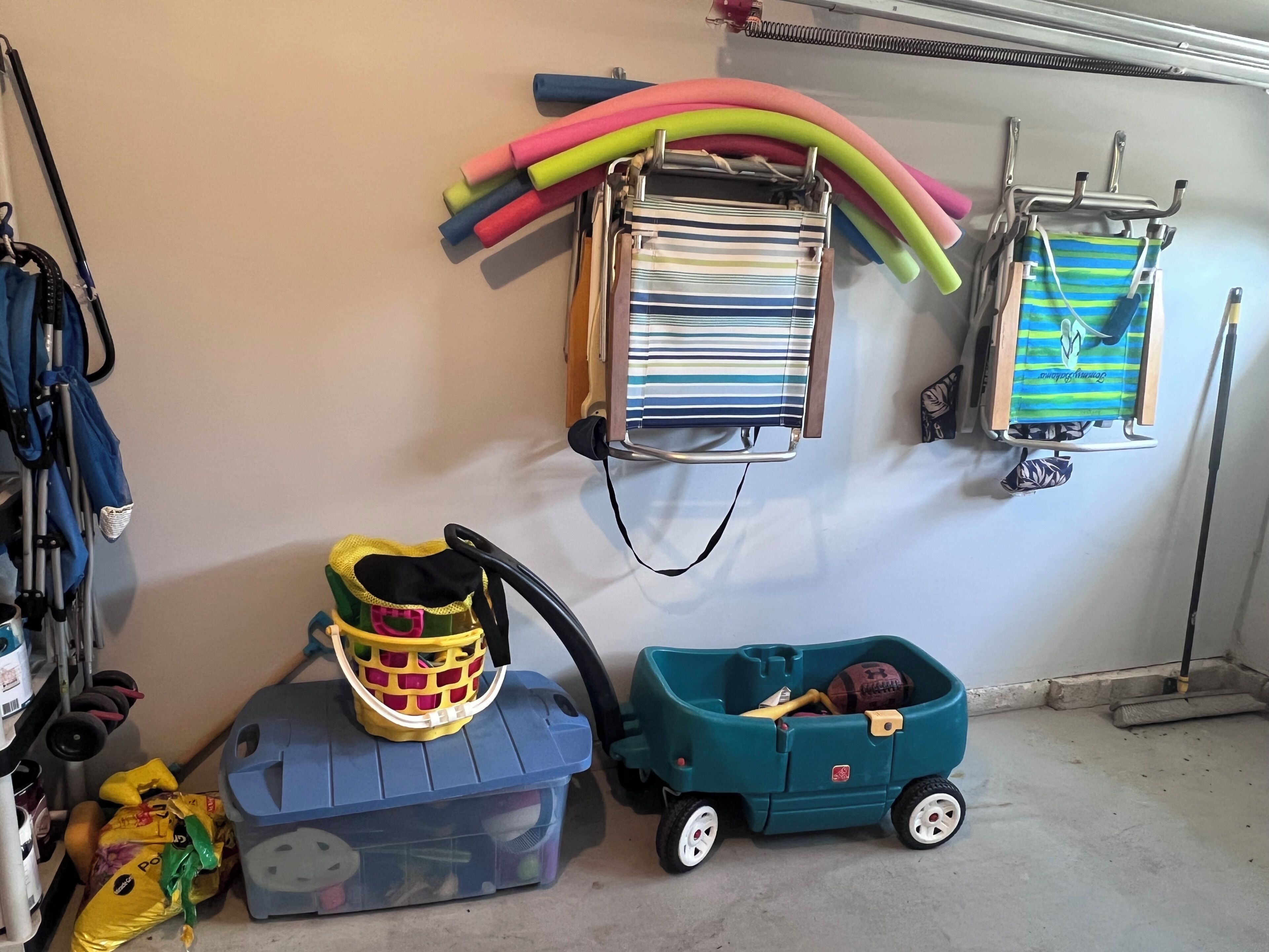 A garage with a toy car, a toy truck, and a storage bin.
