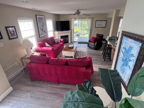 A living room with a red sofa, a coffee table, a fireplace, and a television. - Convenient location in Rehoboth beach. Two master suites, pool - 4BR-3.5BA (Rehoboth Beach)