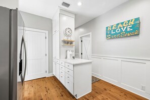 Una cocina moderna con muebles blancos, una cafetera empotrada y un reloj en la pared.