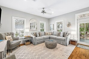 Un salon moderne avec un canapé d’angle, une table basse ronde et un ventilateur de plafond.