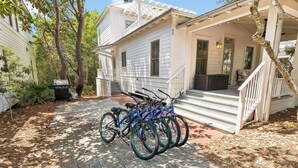 Una propiedad residencial con entrada pavimentada, un porche con escalones y una fila de bicicletas estacionadas afuera.