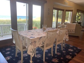 Uma área de refeições com uma mesa posta para quatro pessoas, com vista para a praia.