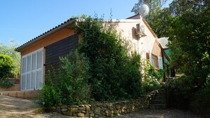 Une maison avec un mur en pierre, une antenne parabolique et une allée gravillonnée.