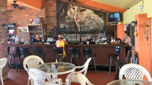 Un bar avec une fresque murale, des tabourets et des tables.