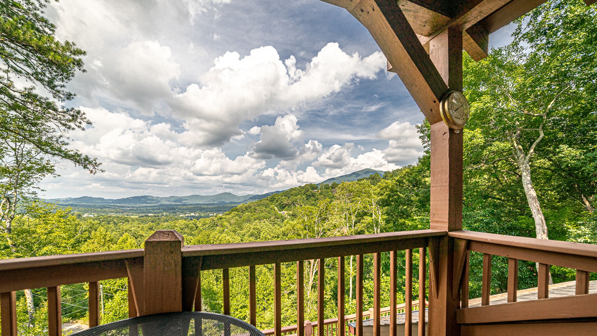 A wooden deck with a view of a lush green landscape and mountains in the distance.