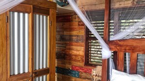 A room with a bed, a wooden wardrobe, a mosquito net, and a window with wooden shutters. - Treehouse Hideaway Villa I--A Nature Packed Soufriere Experience (Soufriere)