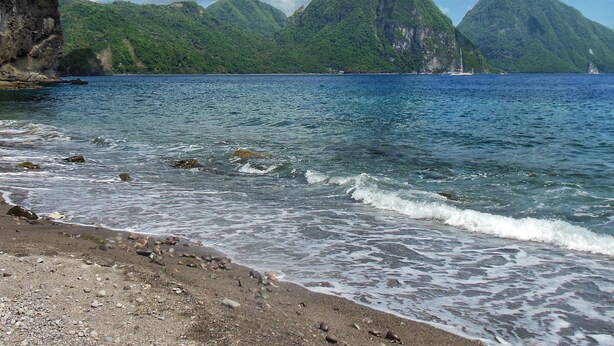 A beach with clear water, rocky shore, and green mountains in the background. - Treehouse Hideaway Villa I--A Nature Packed Soufriere Experience (Soufriere)