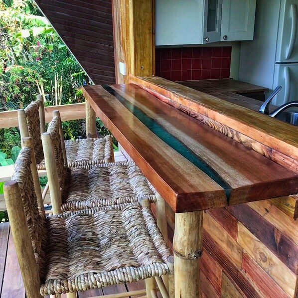 A wooden deck with a long table and woven chairs.