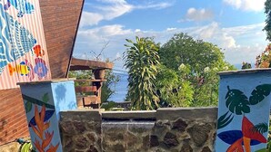A swimming pool with a stone wall and colorful murals, surrounded by potted plants and a clear sky. - Treehouse Hideaway Villa I--A Nature Packed Soufriere Experience (Soufriere)