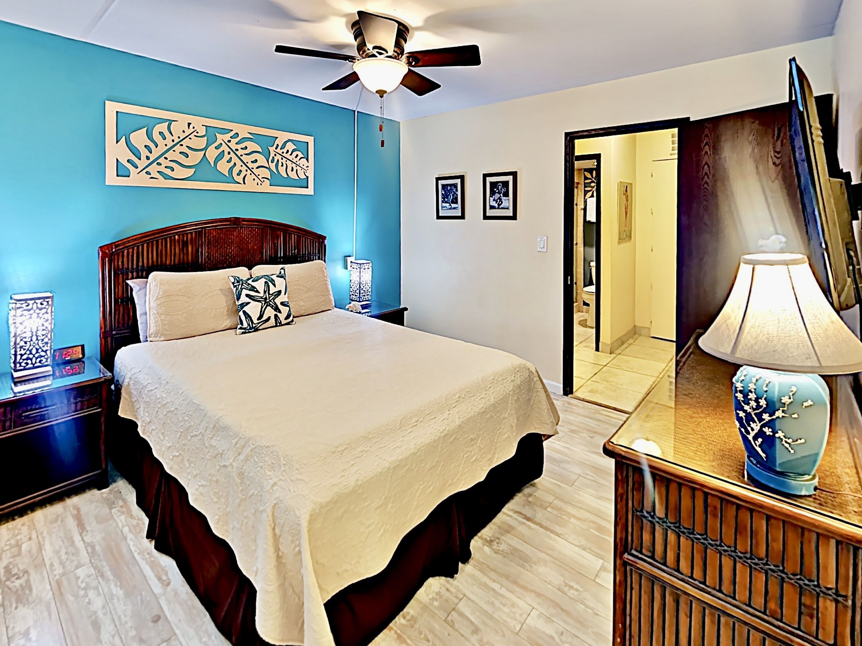 A bedroom with a bed, a nightstand, a lamp, a ceiling fan, and a mirror.