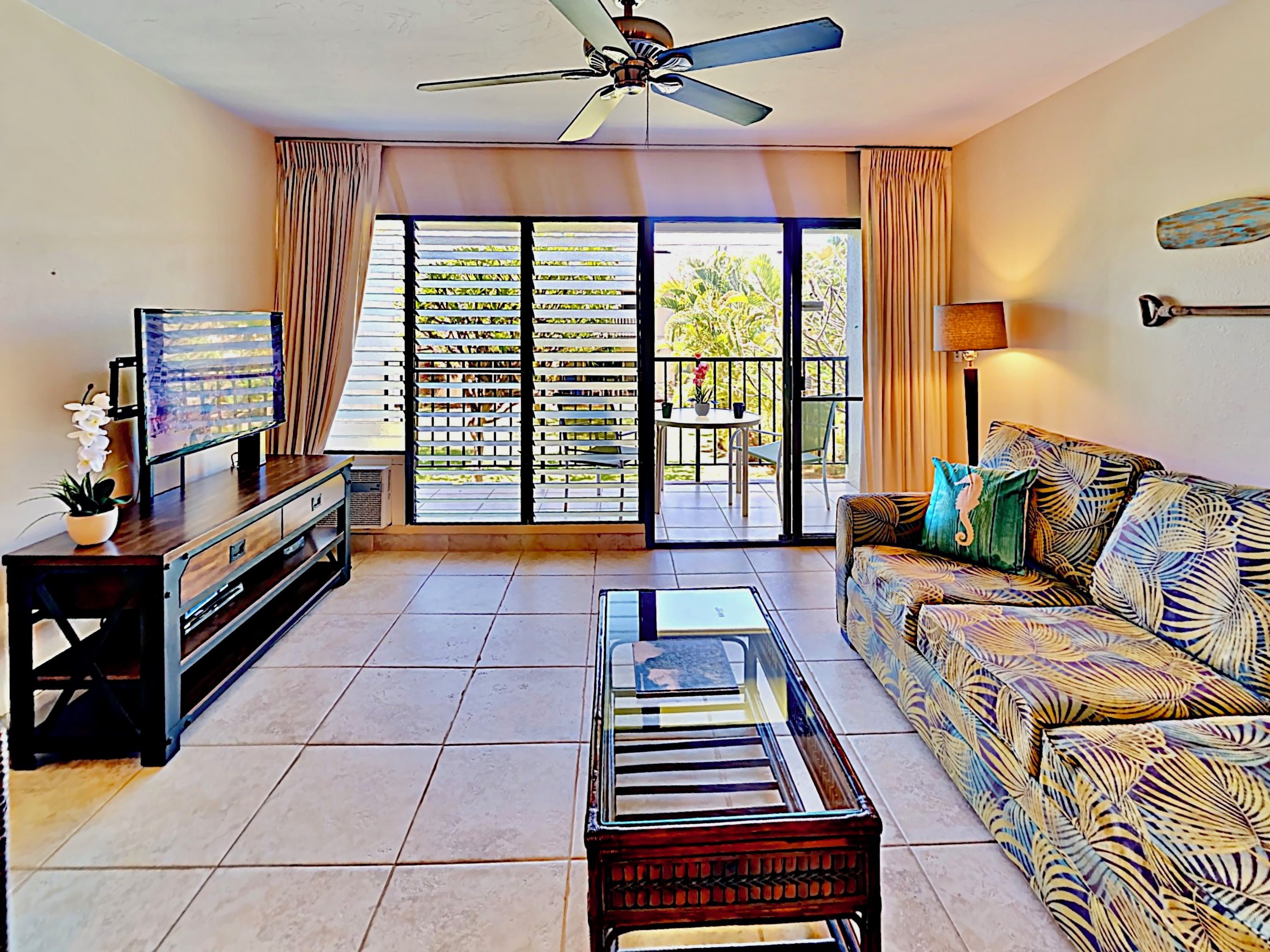 A living room with a sofa, coffee table, TV, and a ceiling fan.