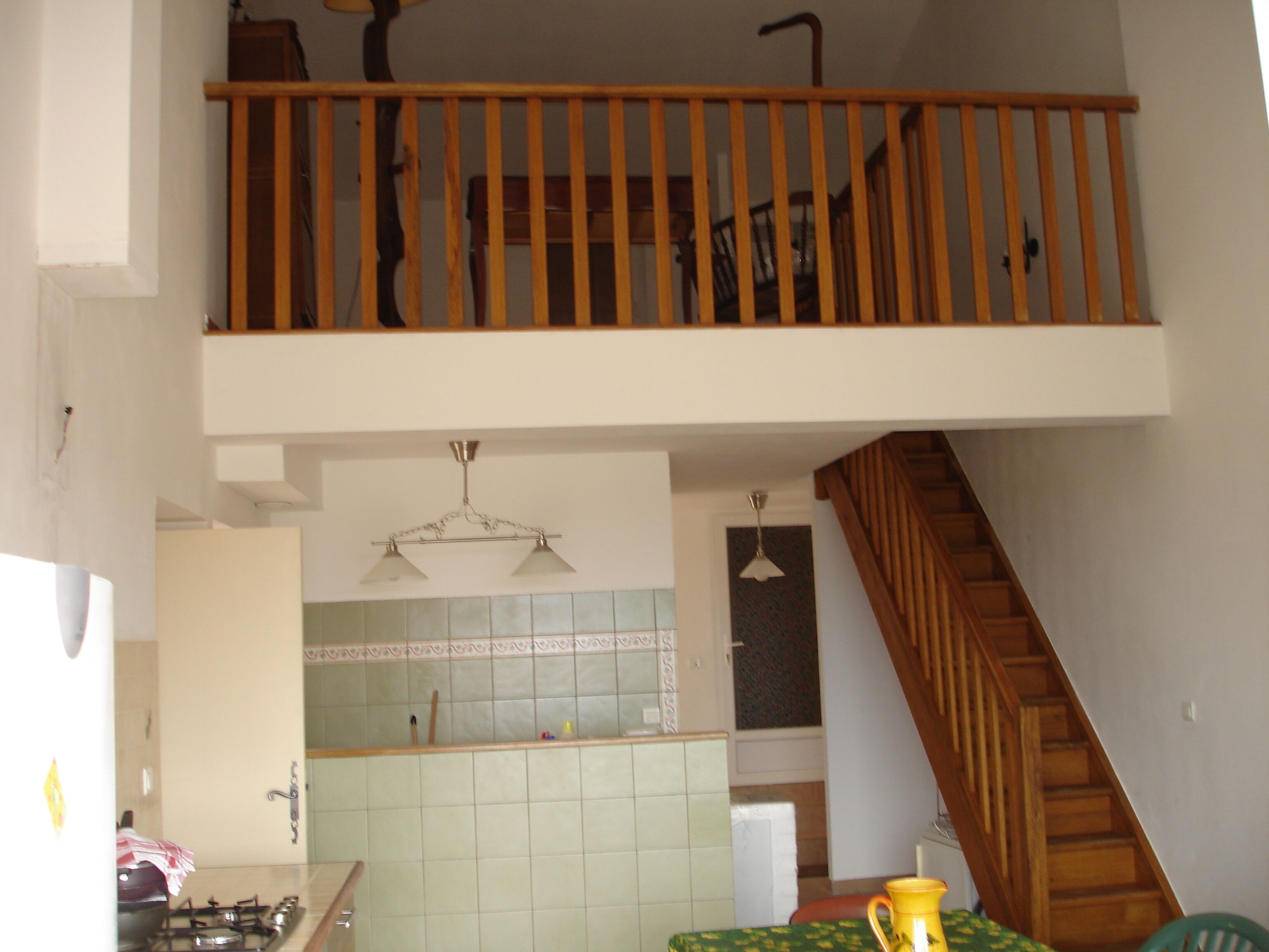 Een keuken met een houten trap, een betegelde spatwand en een hanglamp.