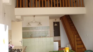 A kitchen with a wooden staircase, a tiled backsplash, and a hanging light fixture. - Close to the Gorges du Verdon Apartment with garden, terrace, panoramic view (Puimoisson)