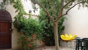 A courtyard with a tree, a stone wall, and a wooden door. - Close to the Gorges du Verdon Apartment with garden, terrace, panoramic view (Puimoisson)