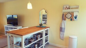 A kitchen with a wooden countertop, a TV, a mirror, and a shelf with kitchen utensils. - We welcome Short & Long Term Guest .  (Aiken)