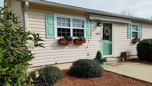 A single-story house with a green door, numbered 143, and two flower boxes on the windowsills. - We welcome Short & Long Term Guest .  (Aiken)