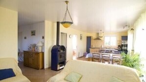 Een gezellige woonkamer met een bank en een eethoek op de achtergrond.