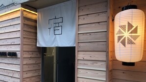 A wooden building entrance with a sign reading "ROOM" and a traditional lantern. - Santiago Guesthouse Naha - Hostel (Naha)