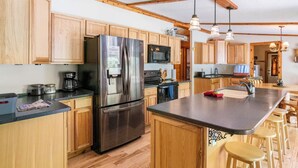 A modern kitchen with wooden cabinets, stainless steel appliances, and a central island with stools.