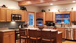 Una cocina moderna con armarios de madera, electrodomésticos de acero inoxidable y una isla grande con taburetes de bar.