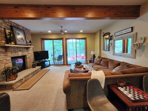 A living room with a fireplace, a television, a sofa, a coffee table, and a chessboard.