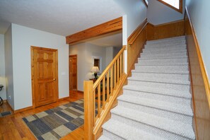 A staircase with wooden railings and carpeted steps leading to an upper floor. -  AMAZING LAKE FRONT 7 BR Home, Hot Tub, Fire Pit, Dock, Pool Table, NEW FIRE PIT (Oakland)