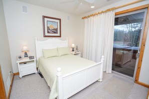 Un dormitorio con cama, mesitas de noche, una ventana con cortinas y vistas al exterior.