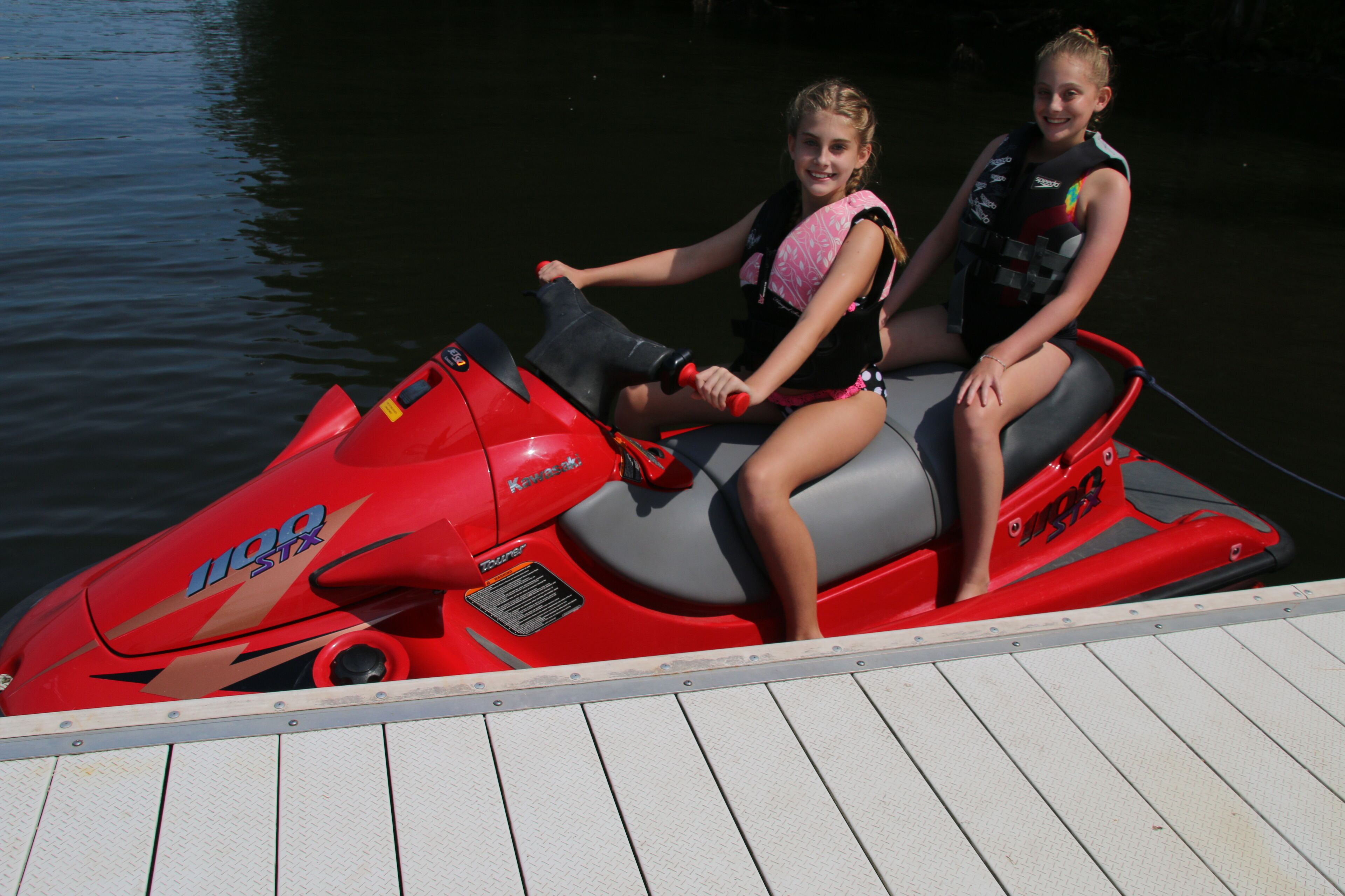 Dos personas en un jet ski rojo en un muelle.